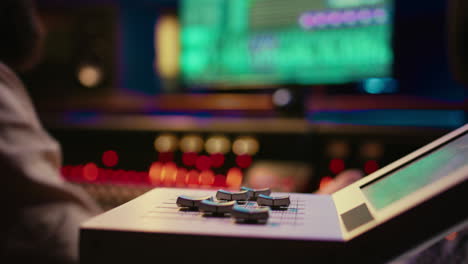 sound engineer operating on motorized faders controller in professional studio