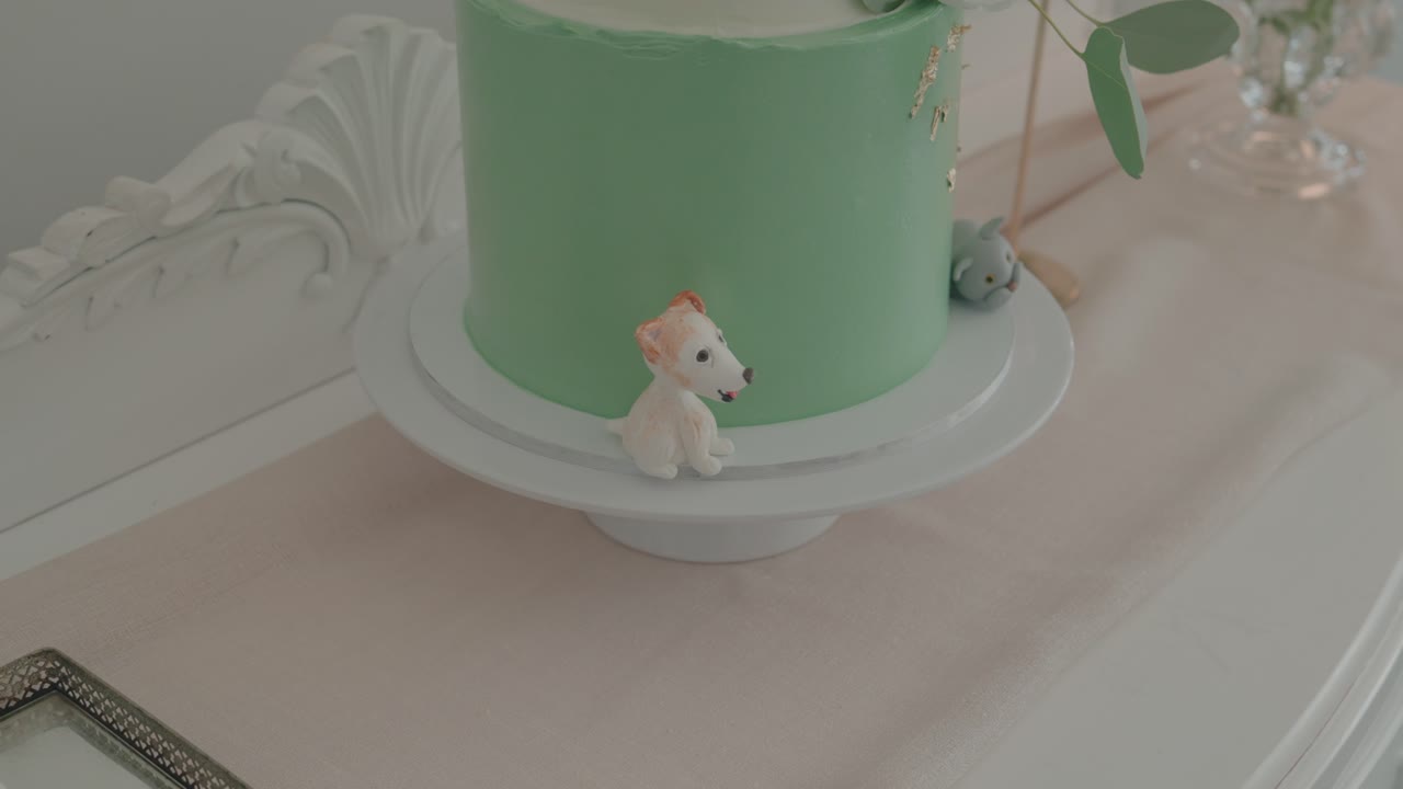 Bánh kem xanh lá cây trên kệ với các bức tượng nhỏ hình động vật và đồ trang trí mềm mại