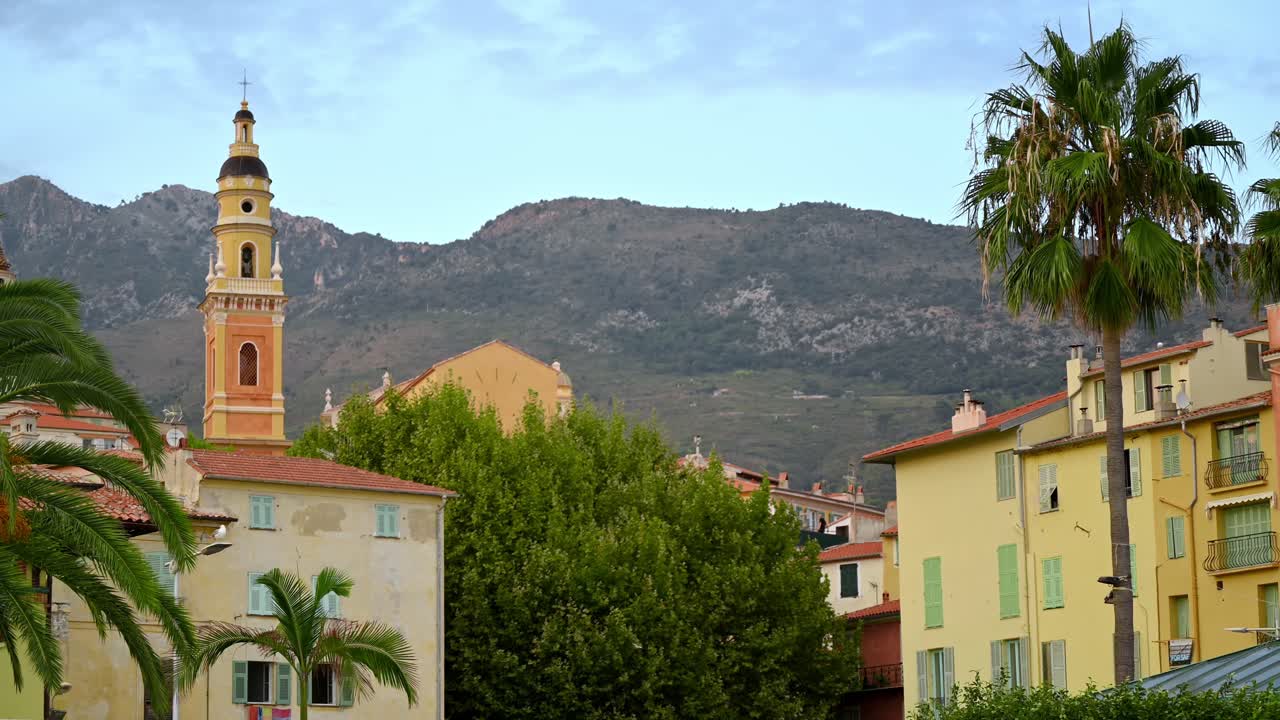 Cityscape of Menton, France. Traditional residential buildings, greenery, Basilica St. Michel