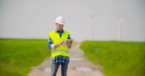 engineer using digital tablet while wind turbine inspection at windmill farm 4