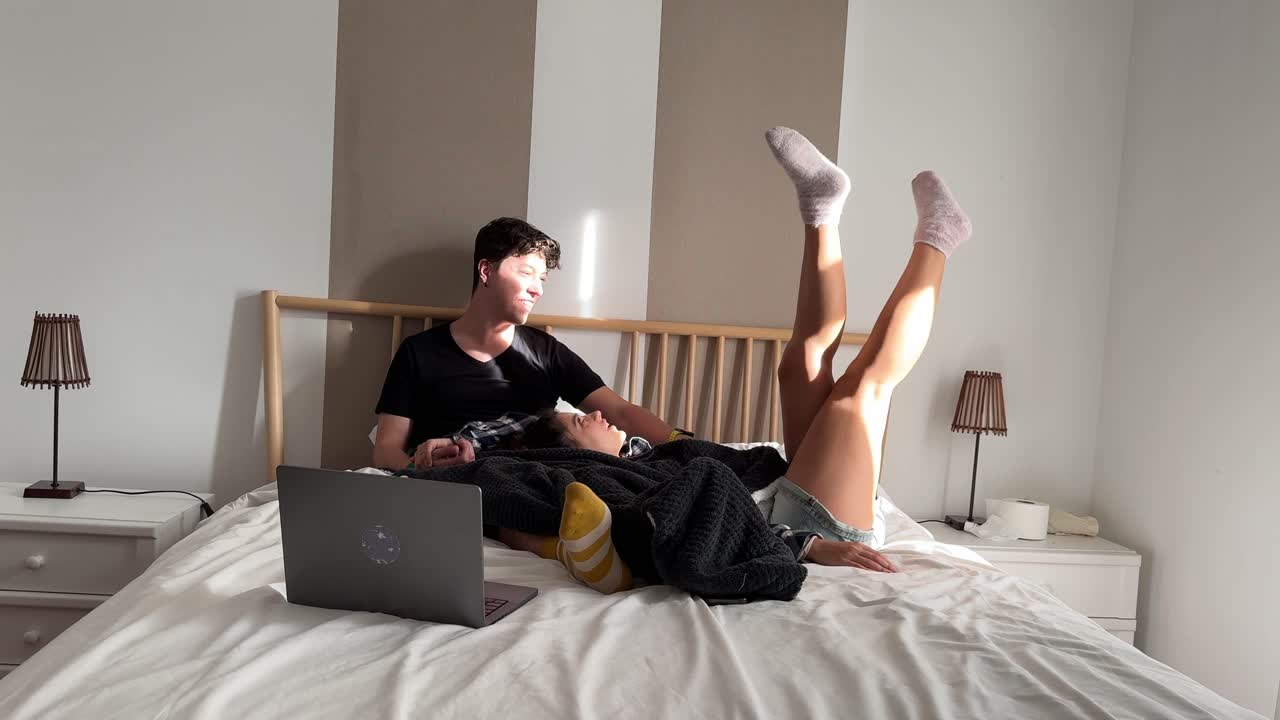Couple Relaxing on a Bed Watching Laptop