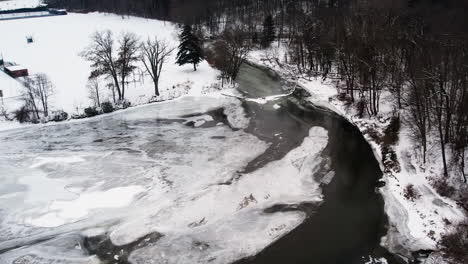 curvas de río cubiertas de nieve y hielo alrededor de campos atléticos blancos en invierno