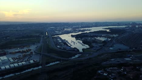 footage-of-sunset-overlooking-yachts-moored-with-traffic-on-a-road-and-shipping-containers-to-be-transported-to-ships-by-trucks