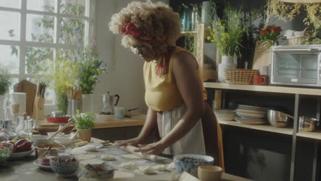 woman preparing dough with a rolling pin in a kitchen