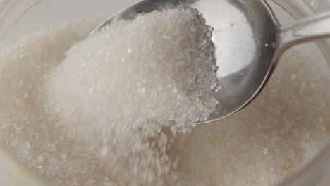 a spoon scooping sugar out of a plastic container