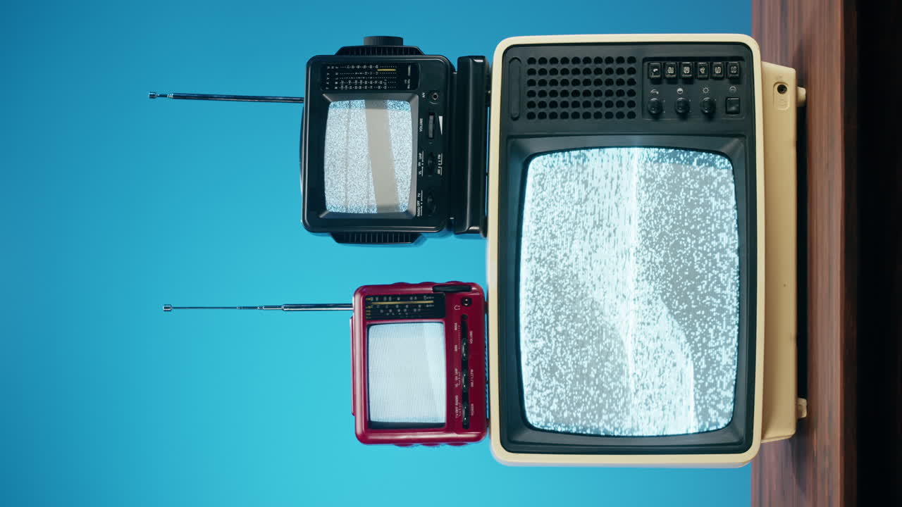 Three vintage televisions with static on their screens