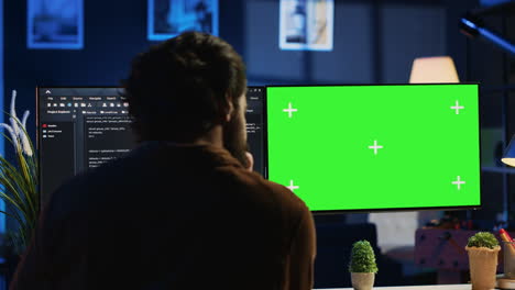 Programmer-typing-complex-code-on-green-screen-computer-in-neon-lit-home-office