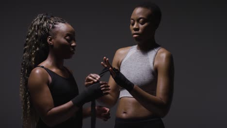 studio shot of women putting on boxing wraps on hands before exercising together 7