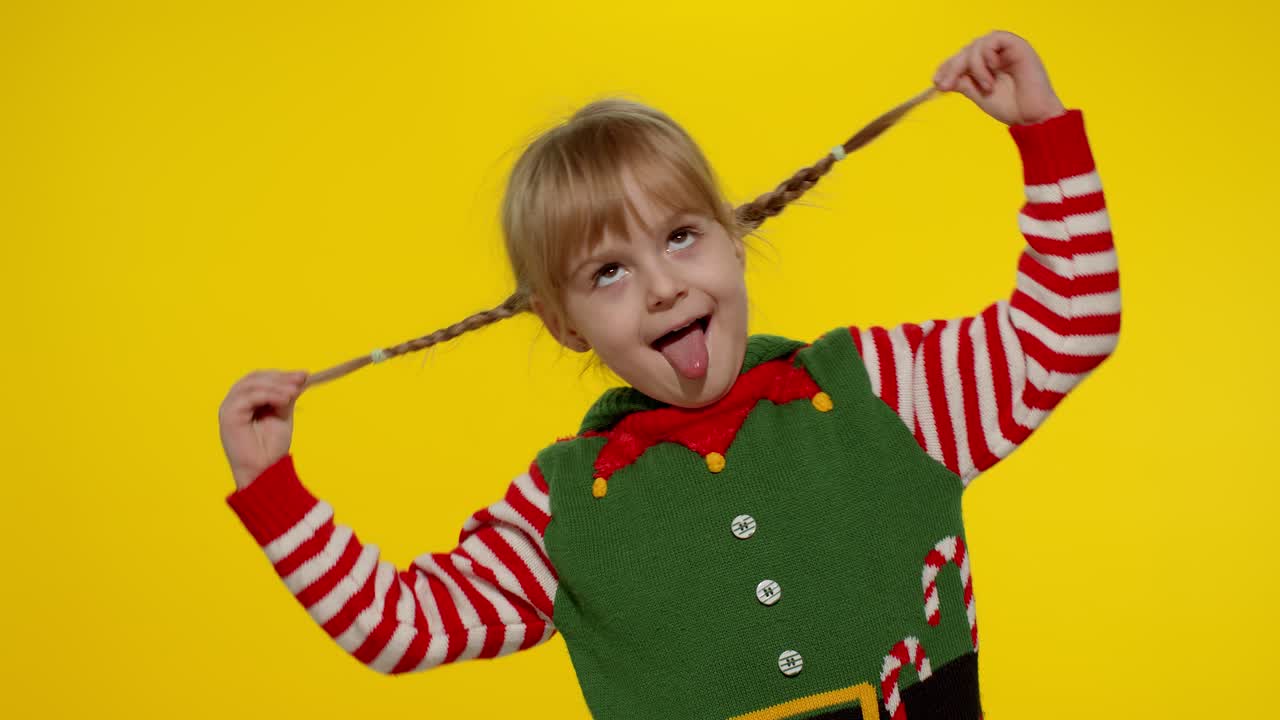 クリスマスエルフのサンタヘルパーの衣装を着て、踊ったりふざけたりしている少女。新年の祝賀。