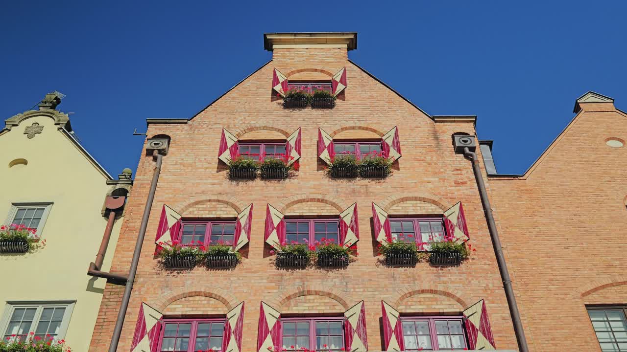 Low angle view of red shuttered brick facade with window flowers, Gdańsk Poland