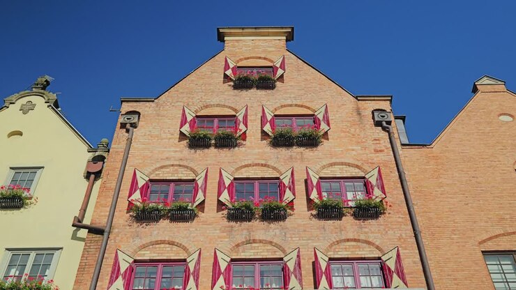 Vista en ángulo bajo de una fachada de ladrillo rojo con contraventanas y flores en las ventanas, Gdansk, Polonia