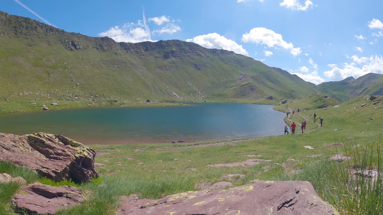Timelapse of a mountain lake in summer with some excursionists