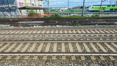 green train moving along tracks in milan, italy