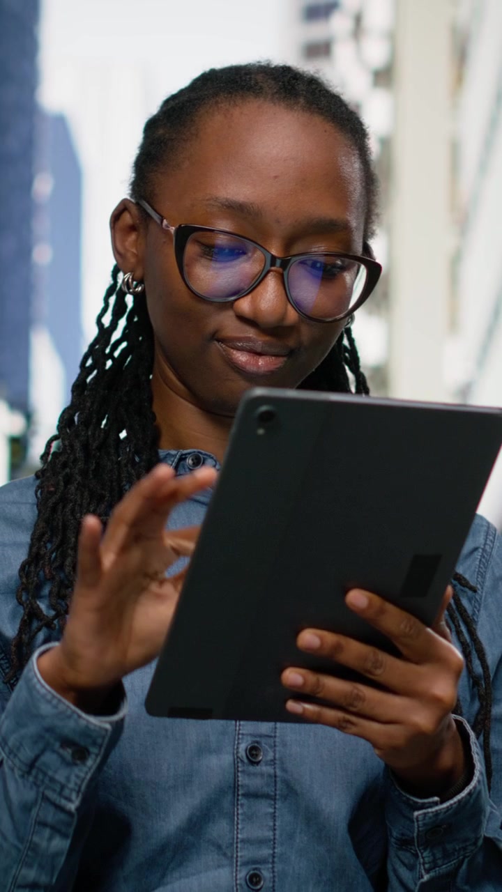 Vertical Video Smiling african american woman using tablet and walking in the city center