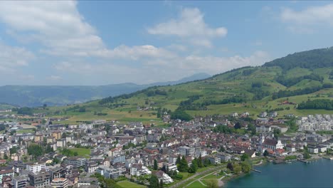 kussnacht flyover: moving over scenic water valley and village in alps mountains, switzerland, europe, drone | dramatic cinematic flyover of homes in village city along vast lake and countryside