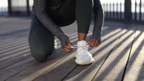 woman in sportswear tying is her shoes outdoor, preparing for workout and running