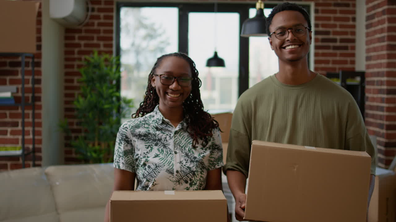 Portrait of african american couple holding cardboard boxes