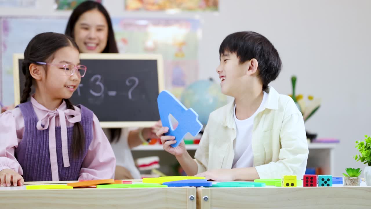 アジアの小学生が文字ブロックを使って数学の問題を解き、先生が黒板を持っている様子