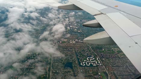 Szenische-Aufnahme-Aus-Dem-Flugzeugfenster-Des-Flugzeugflügels,-Während-Er-Tagsüber-über-Die-Stadt-Fliegt