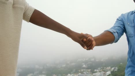 Mid-section-of-African-american-couple-walking-with-hand-in-hand-on-the-beach-4k