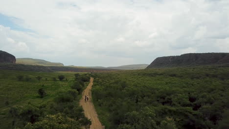 aerial zoom in view of a group of cyclists riding on a kenyan dirt road