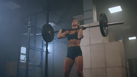 strong woman weightlifting. athletic beautiful woman does overhead deadlift with a barbell in the gym. gorgeous female professional bodybuilder workout weight lift exercises in the authentic fit