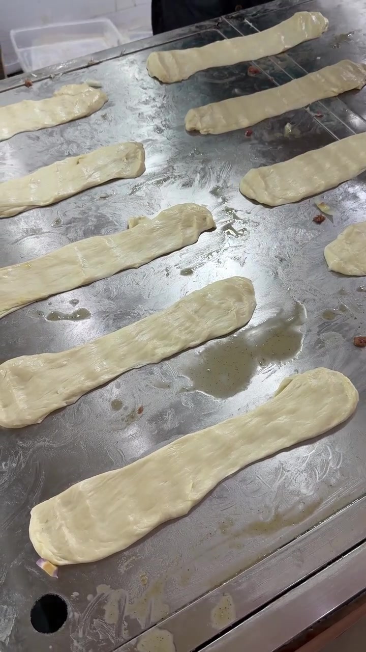 Chef Preparing Dough Strips on a Hot Griddle in a Kitchen