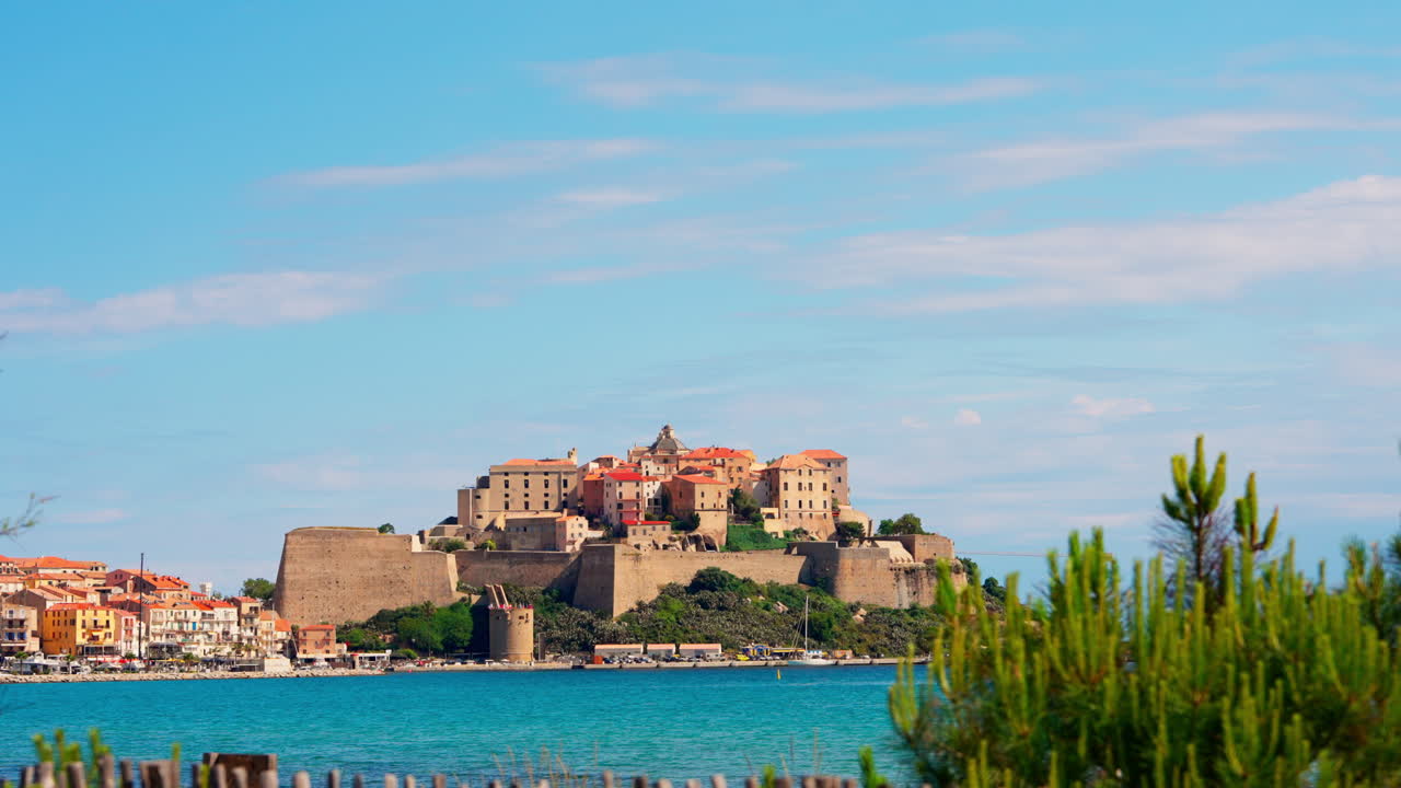 Static shot of the historic town of Calvi in Corsica, France. View of the bastion Citadel overlooking the town. Calm turquoise sea. Summer holidays destination. Mediterranean island