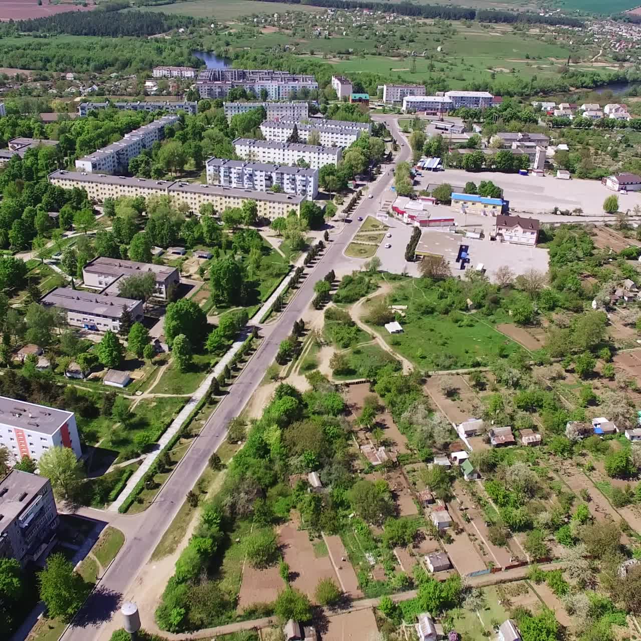 City scenery on amazing sunny day. Green residential areas crossed by roads. Rural area and river at backdrop