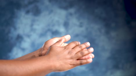 adult african female hands rubbing and moisturizing on a blue background