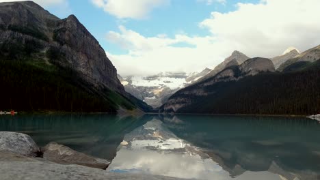 Ein-Hervorragender-Zeitraffer-Während-Des-Sonnenaufgangs,-Aufgenommen-Mit-Einer-Dji-Osmo-Action-kamera-Von-Lake-Louise-In-Alberta,-Mit-Wolken,-Die-über-Die-Berge-Ziehen,-Und-Der-Spiegelung-Der-Berge-Im-Klaren-Wasser