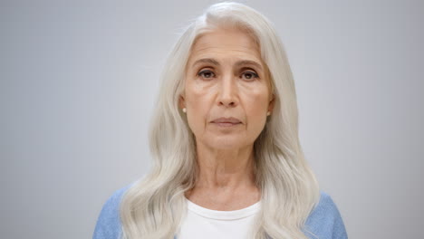 beautiful woman looking camera in studio. old lady posing on grey background.