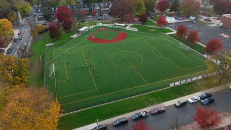 órbita aérea alrededor del equipo de fútbol practicando en un campo de usos múltiples en américa durante el otoño