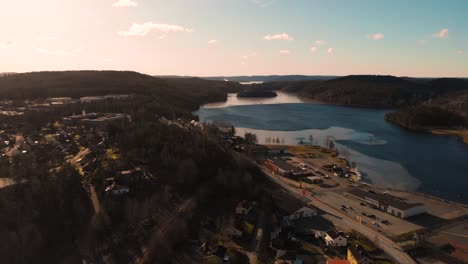 Toma-Aérea-De-Drones-De-Una-Ciudad-Rural-Ubicada-Al-Lado-De-Un-Hermoso-Lago-Durante-La-Puesta-De-Sol