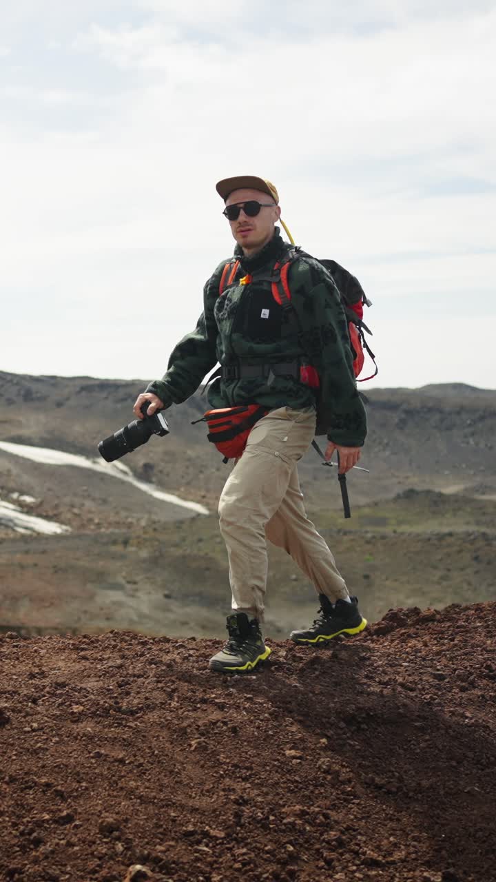 Man Hiking with Backpack and Camera in Barren Mountain Landscape