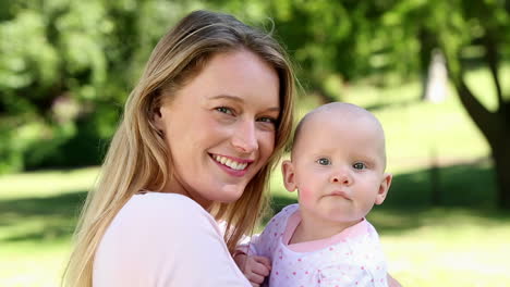 glückliche mutter hält ihr baby im park