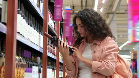 mujer eligiendo vino rojo en una tienda de comestibles