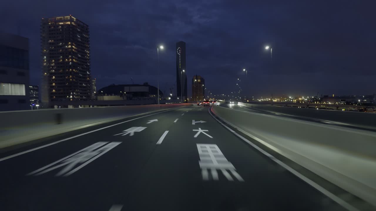 Tokyo Highway at Night: New Territories Drive Capture the allure of Tokyo’s new territories from the car front view, with neon lights and cityscapes in the distance