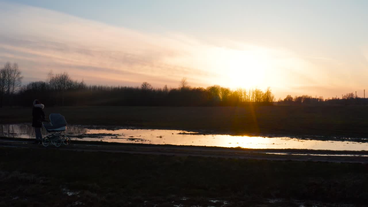 el reflejo del atardecer en un campo inundado, una madre soltera con un cochecito disfrutando del tiempo.