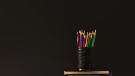 video of container with colorful crayons on black background with copy space