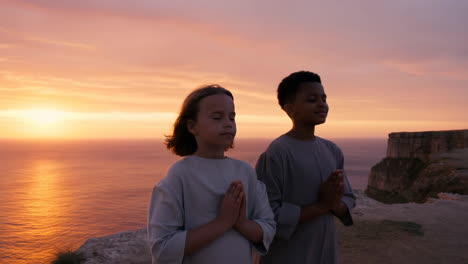 two children meditating at sunset by the ocean