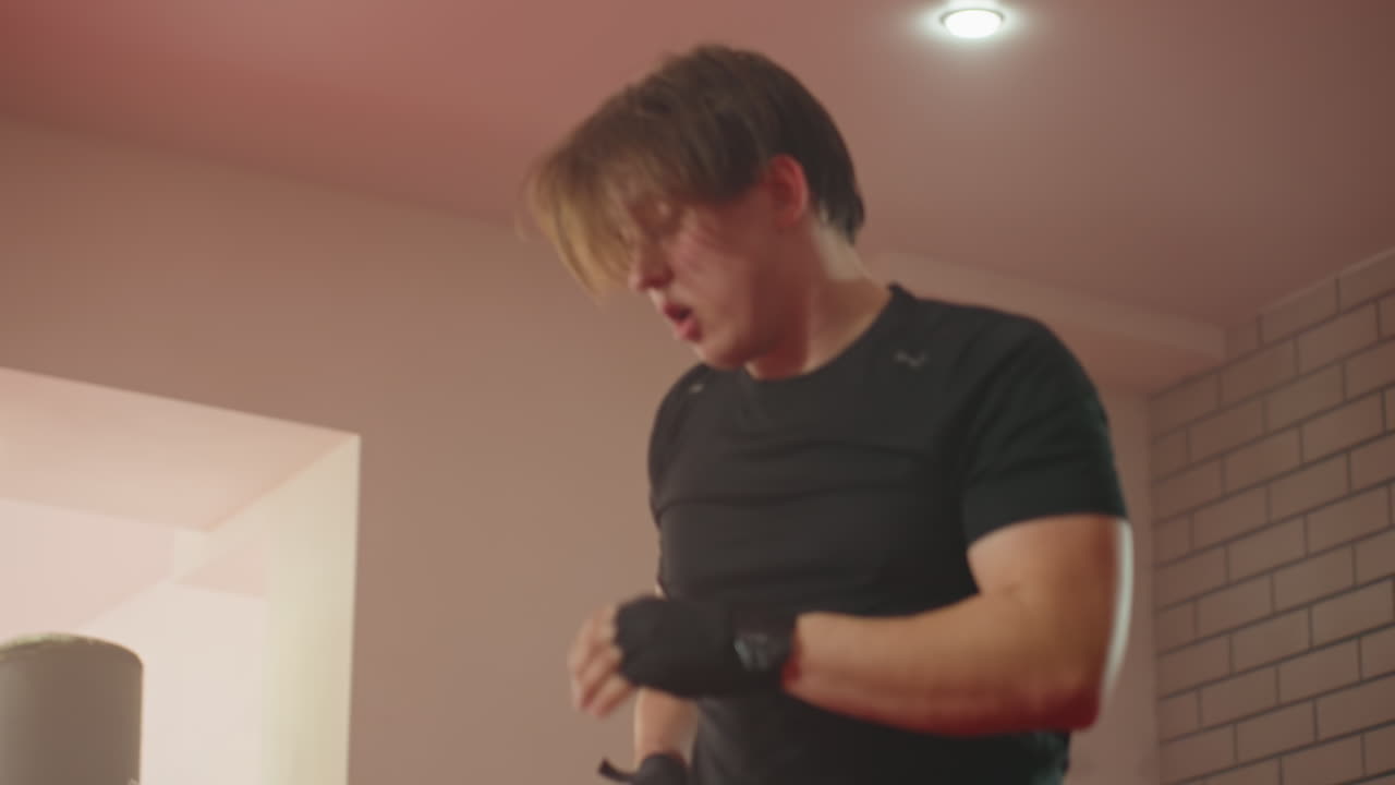 Athlete in black sportswear performs intense combat training move inside gym, showing power, effort,discipline during martial arts session with dynamic motion and strong physical exertion