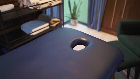 cámara de panorámica lenta toma de mesa de masaje y habitación en el hotel, argentina. paredes de madera, silla verde y mesa de bandeja en la escena.