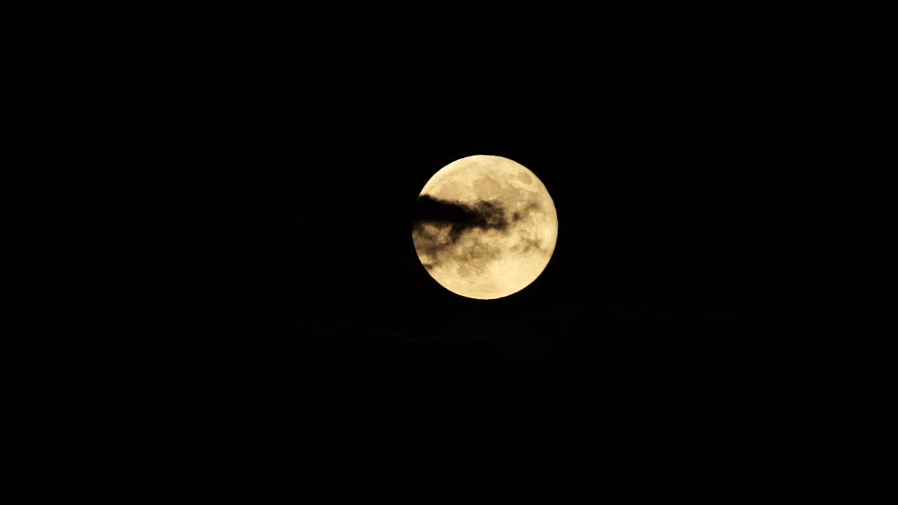 Lua cheia nascendo por trás das nuvens contra o céu escuro
