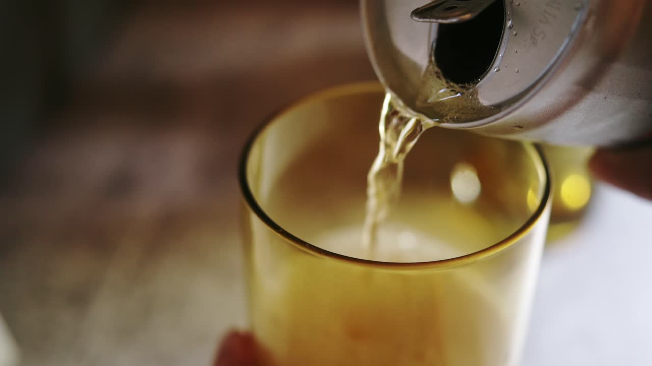 Golden soda poured from a can into a glass, close-up view showing refreshing bubbles and smooth liquid flow. 30 fps