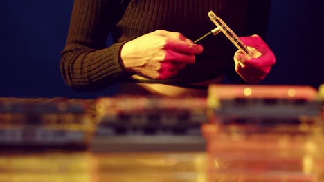 woman using a tool to wind the tape on a vintage cassette - sliding view with stacks of cassettes in the foreground