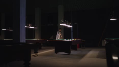 hombre jugando al billar en una oscura sala de billar