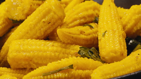 close-up of fermented yellow mini corn with black pepper on plate. preservation of vegetables in glass jars. fermentation preserved mini corns with spices macro.