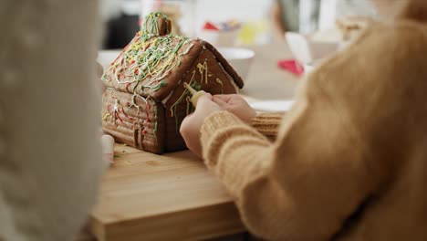 detail video of children and mother decorating gingerbread house