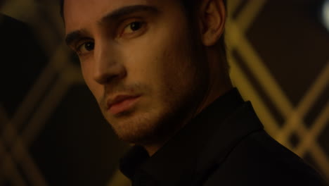 Beautiful guy turning head blurred background. Young man looking camera indoors.